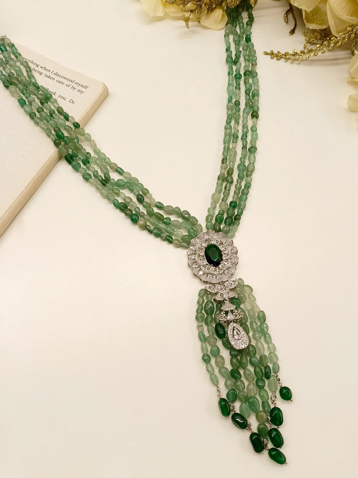 Necklace pendant featuring an emerald stone set into an American diamond frame