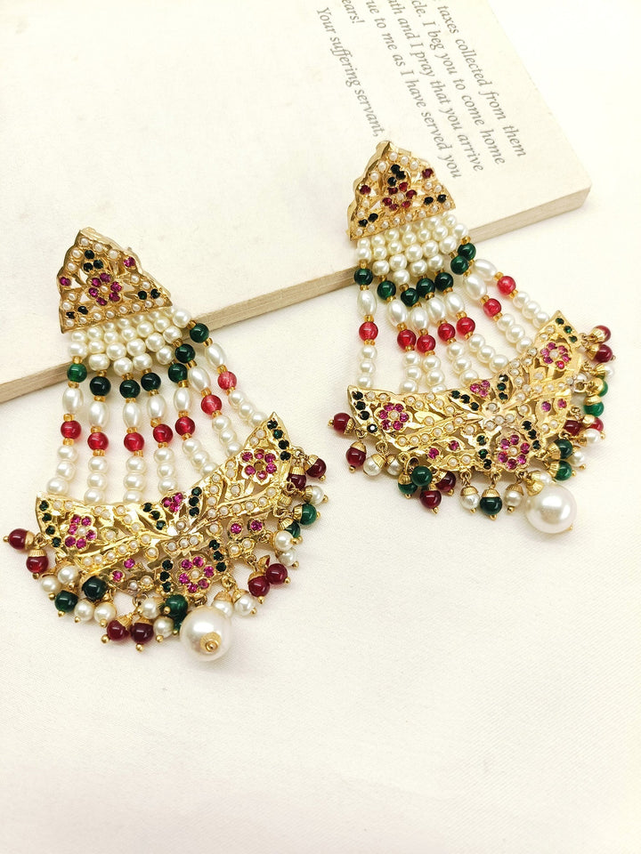 Traditional long jadau earrings with intricate gold texture work and ruby and green bead accents with small bead hangings 