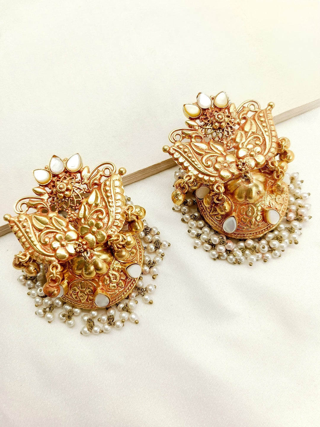 Beautifully designed traditional gold carving jhumkas with kundan stones and pearls hangings on gold plated brass metal 