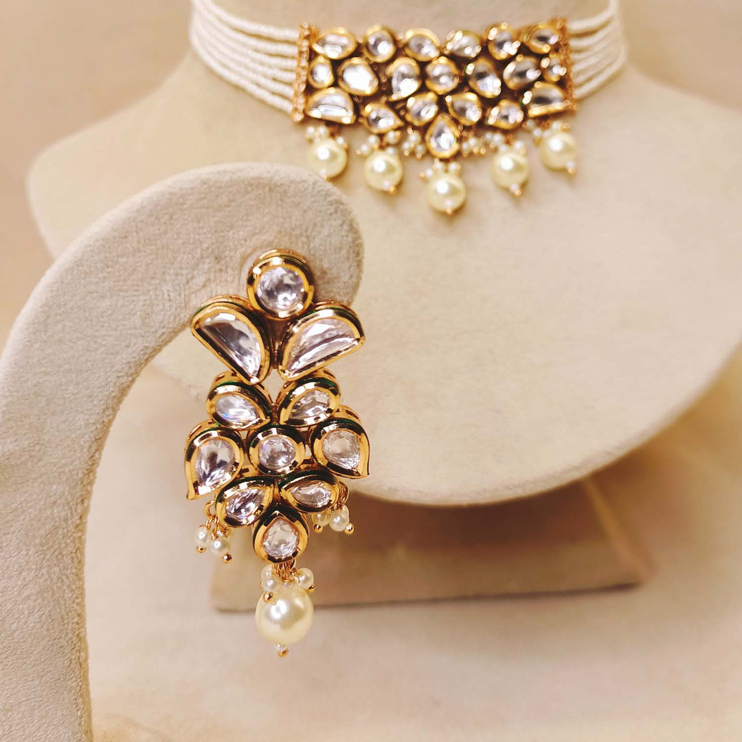 Intricate Kundan choker embellished with white pearls and paired with small Kundan earrings